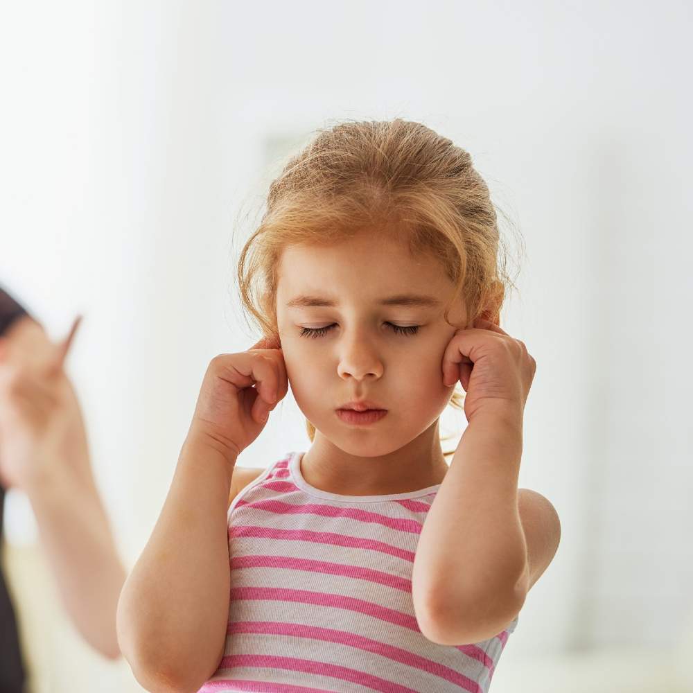 Enfant se bouchant les oreilles, illustrant des difficultés de communication ou de compréhension du langage.