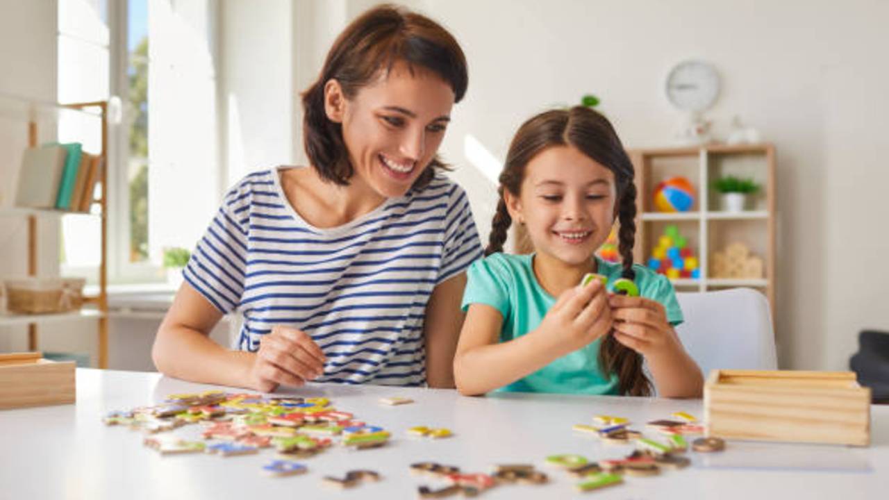 Mère et enfant assemblant un puzzle ensemble, activité de stimulation du langage et des habiletés cognitives.